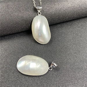 Vue détaillée de pendentifs en nacre naturelle avec reflets irisés sur fond sombre