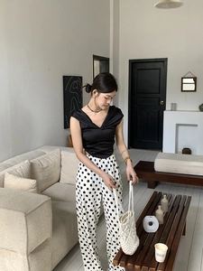 Detail of elegant V-neck sleeveless top and polka dot high-waisted trousers on model