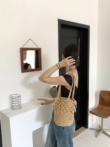 Detailed view of handmade hollow straw bag with woven straps on a shoulder