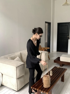 Detail einer braunen Stroh-Eimertasche kombiniert mit minimalistischem schwarzem Outfit