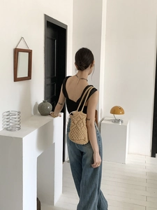 Detailed shot of a beige hand-woven crochet beach bag styled with a minimalist outfit