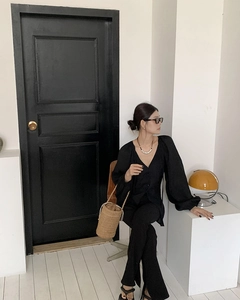 Schicke braune Stroh-Eimertasche kombiniert mit schwarzem Outfit in modernem Interieur