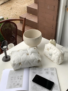 Detail of embroidered rabbit quilted makeup bags on a white table in outdoor light