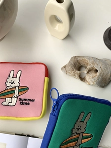 Close-up of summer rabbit embroidery on mini canvas pouch with circular blue zipper pull