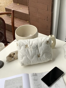 Detailed view of quilted rabbit embroidery cosmetic bag on a cozy minimalist desk setup