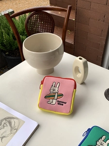 Detailed embroidery of surfing rabbit and Summer Time text on pink mini storage bag