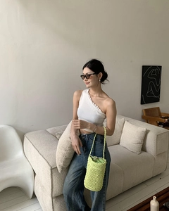 Lässiges Sommeroutfit mit weißem One-Shoulder-Oberteil und leuchtend gelber gewebter Eimertasche