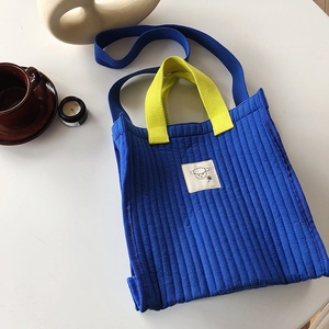 Close-up of blue quilted canvas tote bag with yellow handles and cute sheep patch logo