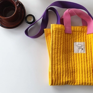 Detailed close-up of quilted yellow corduroy tote bag with cartoon lamb patch decor