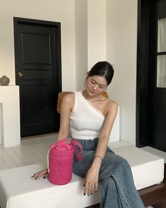 Detail einer handgefertigten gewebten Eimertasche in Pink mit Sommeroutfit