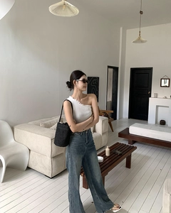 Asiatisches Model mit einer schwarzen Stroh-Eimertasche in hellem nordischem Interieur