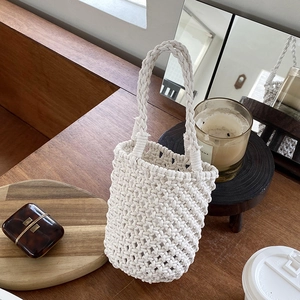 Sac seau tissé main blanc avec texture en maille losange sur table en bois