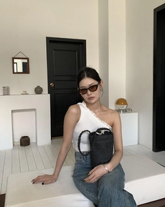 Schicke schwarze Strohtasche kombiniert mit weißem Rippstrick-Top und Jeanshose
