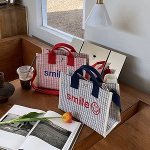 Dettaglio di borse tote in tela intrecciata con ricamo smile su tavolo in legno