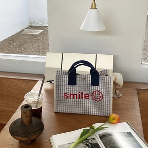 Dettaglio della borsa tote in tela con ricamo smile su un tavolo in legno decorato