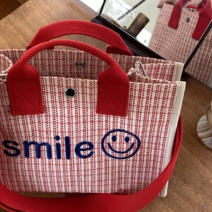 Dettaglio della borsa tote in tela a righe rosse e bianche con ricamo smile e bottone