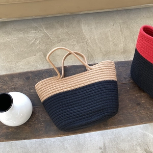 Vue détaillée du sac cabas bicolore en coton tressé posé sur un banc en bois rustique