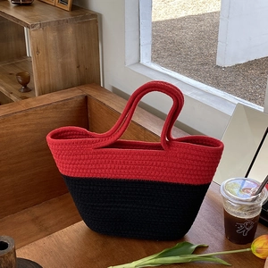 Détail du sac cabas en corde de coton tressé rouge et noir sur une table en bois