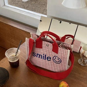 Dettaglio della borsa tote intrecciata rossa e bianca con ricamo smile su tavolo scuro