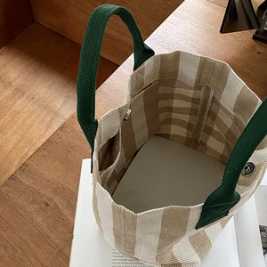 Detail view of canvas tote bag featuring interior pocket and magnetic metal snap closure