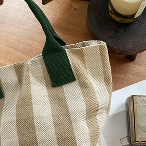 Close-up of canvas tote bag fabric texture with beige stripes and green handles