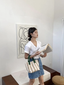 Casual striped canvas tote bag with contrast green handles shown in a lifestyle setting