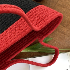 Gros plan sur le tissage artisanal d'un sac en corde de coton bicolore noir et rouge