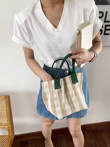 Lifestyle shot of a minimalist striped canvas tote bag with green handles for daily use