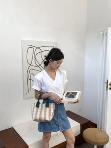 Minimalist canvas tote bag with contrast green handles shown with casual fashion outfit