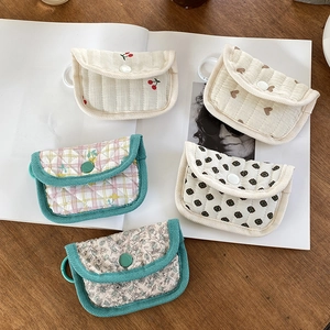 Five assorted quilted floral mini pouches with hooks displayed on a wooden table