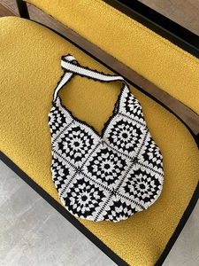 Macro detail of hand-woven crochet granny square pattern on a black and white shoulder bag
