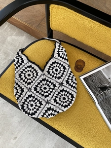 Detail of handmade crochet tote bag with black and white sunflower patterns on a bouclé chair