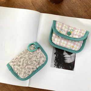 Close-up of quilted floral coin purses with green corduroy trim and ring clip detail