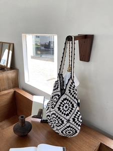 Detail of a handmade black and white crochet tote bag with retro granny square pattern