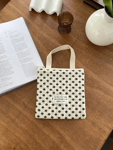 Détail d'un sac matelassé à fleurs avec fermeture éclair sur un bureau en bois