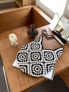 Close-up of handmade crochet granny square patterns on black and white hobo bag