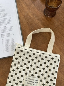 Gros plan de la trousse de rangement matelassée fleurie avec motifs de feuilles et anse