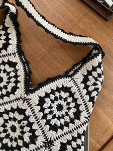Close-up of handmade crochet bag with black and white floral granny square patterns