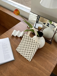 Détail d'un sac à main matelassé à pois sur un bureau dans une ambiance chaleureuse