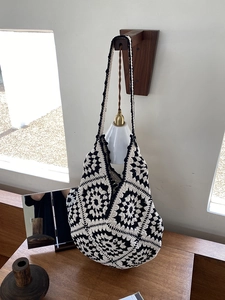 Detail of hand-woven hobo bag featuring black and white floral crochet patterns