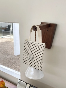 Pochette matelassée en coton à pois noirs avec étiquette texte sur un crochet