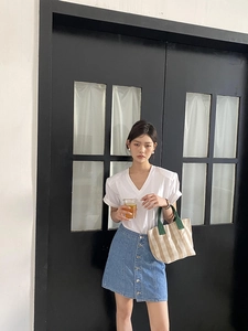 Close-up of a striped canvas tote bag paired with a white T-shirt and blue denim skirt