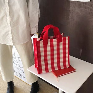 Detail of red and white checkered tote bag with sturdy red handles in casual lifestyle setting