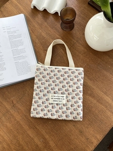 Gros plan de la pochette matelassée fleurie avec écusson sur une table en bois