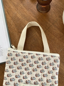 Vue détaillée de la trousse matelassée à motifs floraux sur un bureau en bois