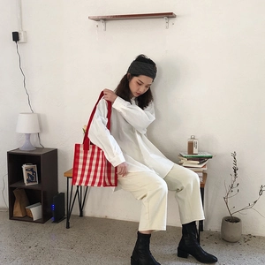Detail of red and white checkered woven tote bag with durable webbed handles