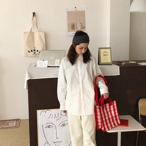 Close-up of a stylish red and white plaid tote bag with loose-fit casual shirt and pants