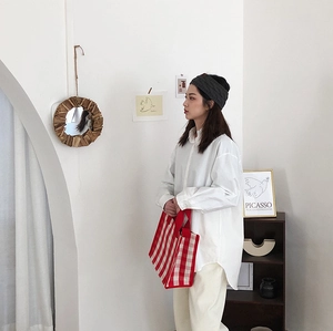 Close-up of a red and white checkered woven tote bag paired with a white oversized cotton shirt