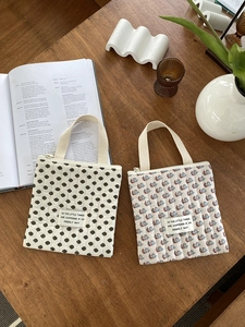 Détail de pochettes matelassées avec motifs floraux et à pois sur un bureau en bois