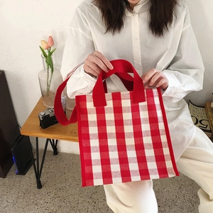 Detail of red and white plaid tote bag with shoulder strap shown in lifestyle setting